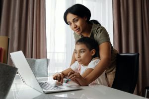 Mother helping daughter use laptop