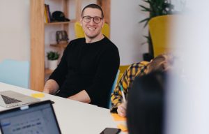 Man smiling from across the table working with others