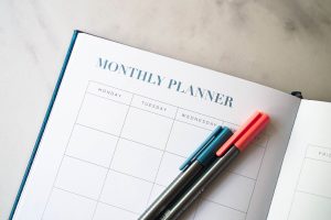 Monthly planner laying open on a table with two markers laid on top