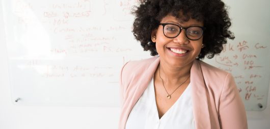 Woman standing in front of whiteboard smiling